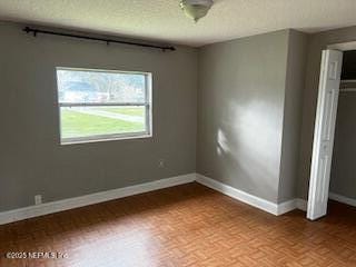 unfurnished bedroom featuring a closet, a textured ceiling, and baseboards