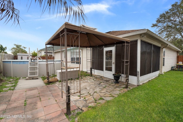 back of house with a gazebo, a yard, a patio, a fenced in pool, and a sunroom