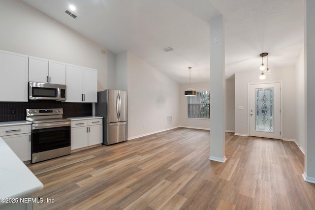 kitchen featuring light hardwood / wood-style flooring, appliances with stainless steel finishes, hanging light fixtures, tasteful backsplash, and white cabinets