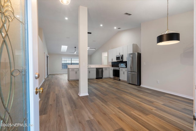 kitchen featuring stainless steel appliances, white cabinetry, hanging light fixtures, and dark hardwood / wood-style flooring