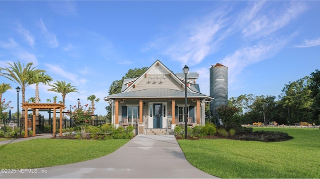 victorian-style house featuring a front lawn, fence, covered porch, metal roof, and a chimney