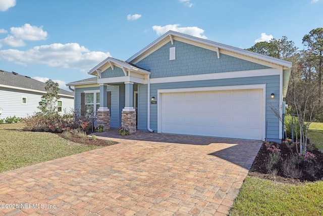 craftsman-style home featuring a front yard, decorative driveway, and a garage