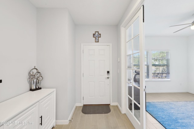 foyer entrance with baseboards, light wood-type flooring, and ceiling fan