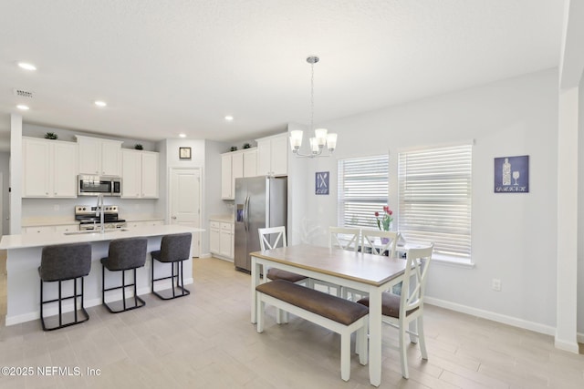 dining area with visible vents, recessed lighting, an inviting chandelier, light wood finished floors, and baseboards