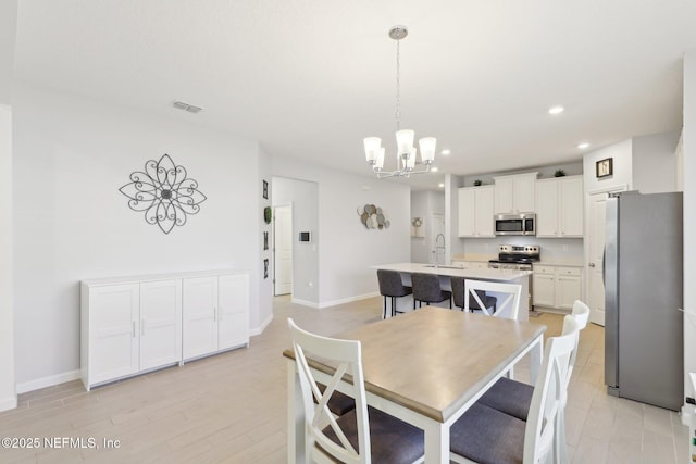 dining area with baseboards, visible vents, light wood finished floors, recessed lighting, and a chandelier