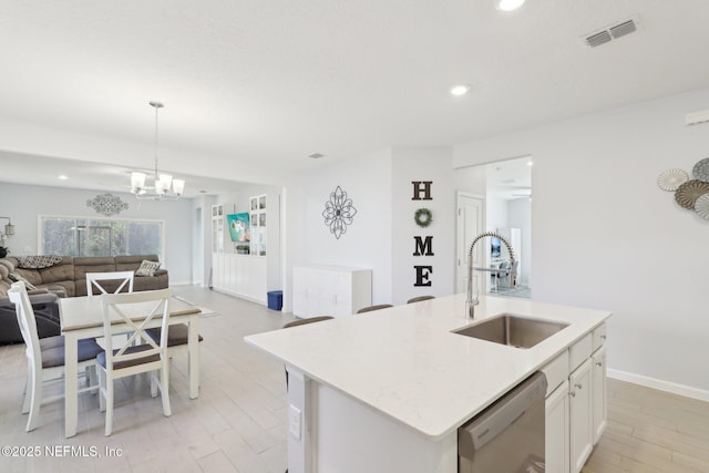 kitchen featuring visible vents, a sink, open floor plan, white cabinets, and stainless steel dishwasher