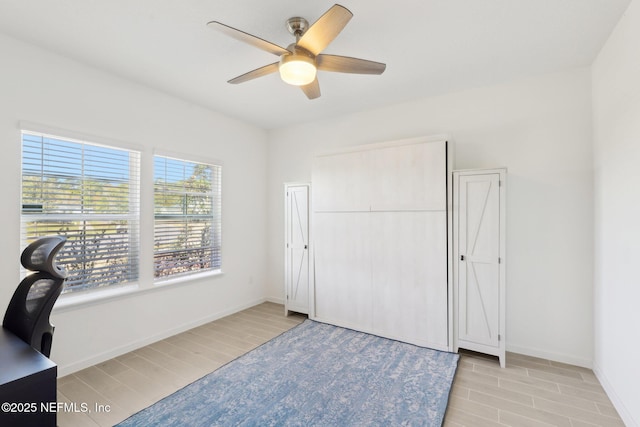 office area with light wood finished floors, a ceiling fan, and baseboards