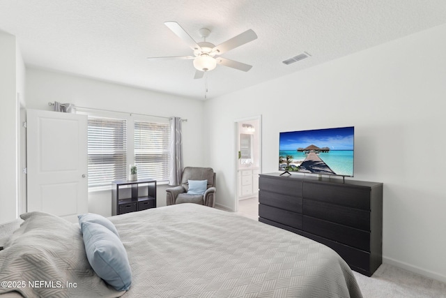 bedroom featuring visible vents, baseboards, carpet floors, a textured ceiling, and ensuite bath