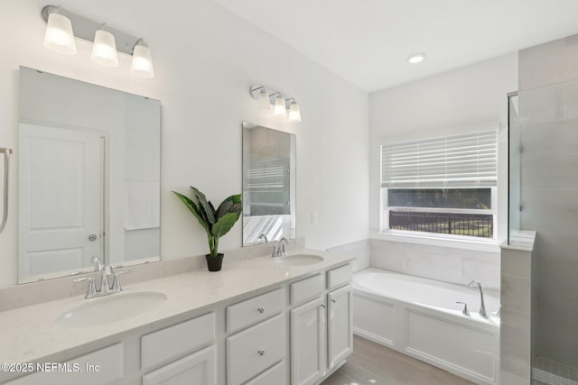 full bathroom featuring double vanity, a tile shower, a garden tub, and a sink