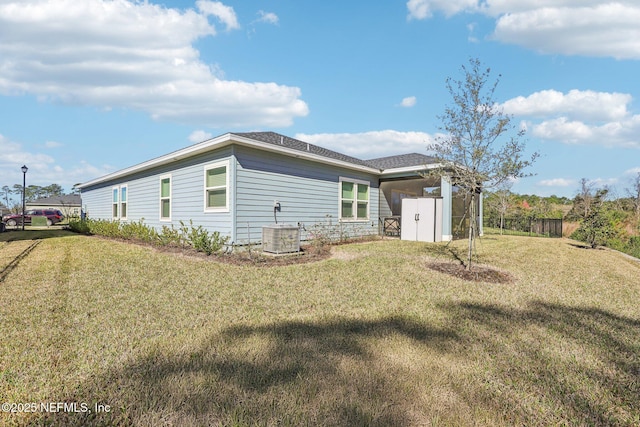 back of property with a lawn, central AC, and fence