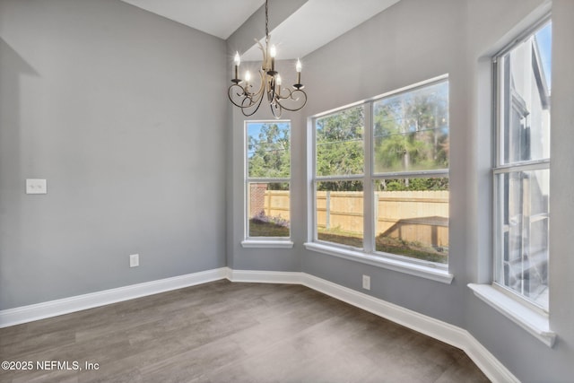 unfurnished dining area featuring a notable chandelier, a wealth of natural light, and dark hardwood / wood-style floors