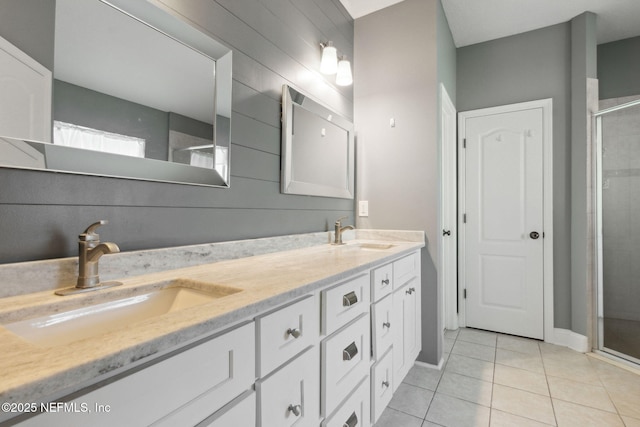 bathroom with a shower with door, vanity, and tile patterned floors