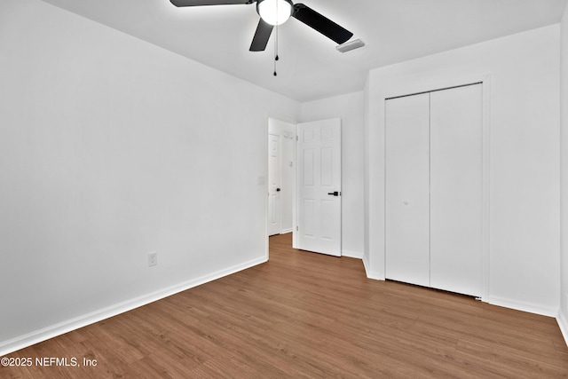 unfurnished bedroom featuring a closet, visible vents, ceiling fan, wood finished floors, and baseboards