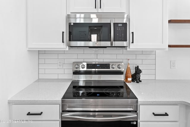 kitchen featuring decorative backsplash, appliances with stainless steel finishes, white cabinets, and light stone counters