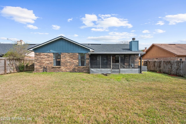 back of property featuring a sunroom, a fenced backyard, a chimney, and brick siding