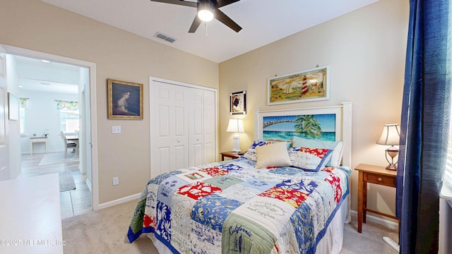 bedroom featuring ceiling fan, light carpet, visible vents, baseboards, and a closet