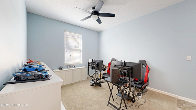 interior space featuring ceiling fan, baseboards, a textured ceiling, and light colored carpet