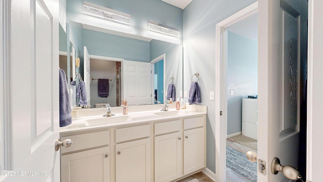 full bath with double vanity, baseboards, and a sink