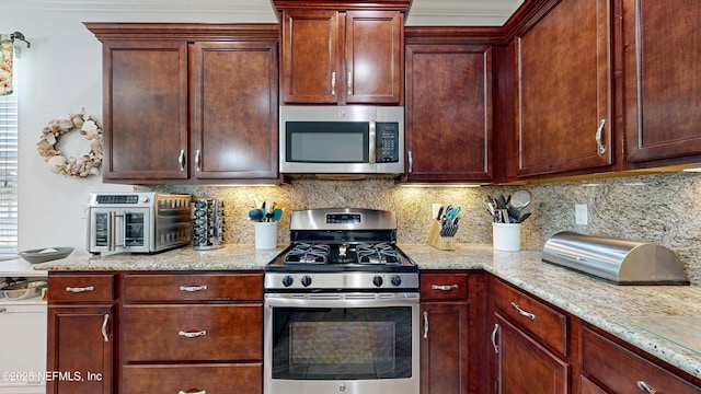 kitchen featuring a toaster, tasteful backsplash, appliances with stainless steel finishes, and light stone counters