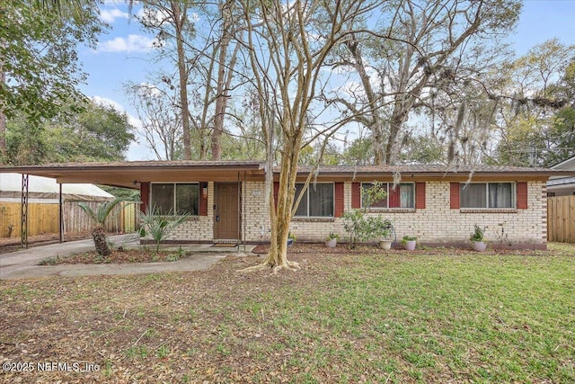 ranch-style home with driveway, an attached carport, fence, a front yard, and brick siding