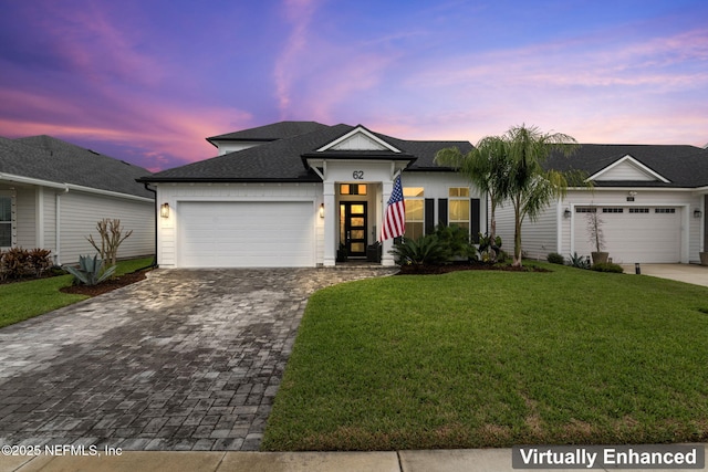 view of front of property featuring an attached garage, a shingled roof, decorative driveway, and a yard