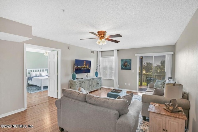 living room featuring wood-type flooring, a textured ceiling, and ceiling fan