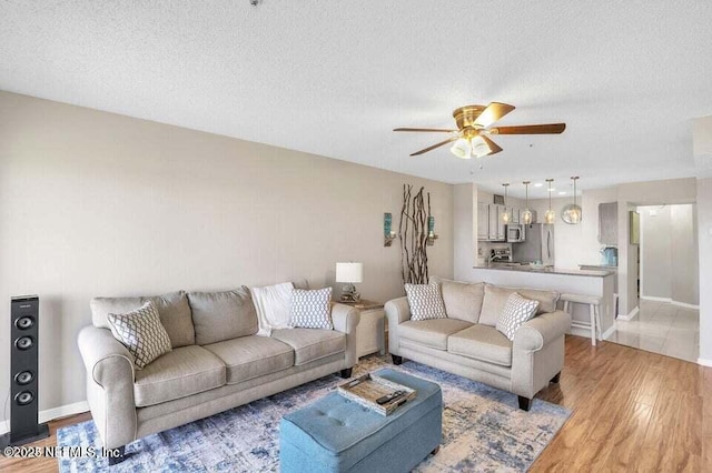 living room with hardwood / wood-style floors, a textured ceiling, and ceiling fan