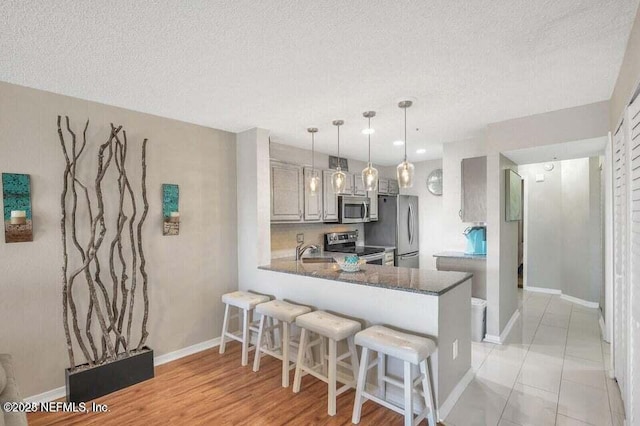 kitchen with sink, decorative light fixtures, a kitchen breakfast bar, kitchen peninsula, and stainless steel appliances