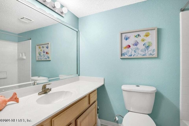 bathroom with vanity, toilet, and a textured ceiling