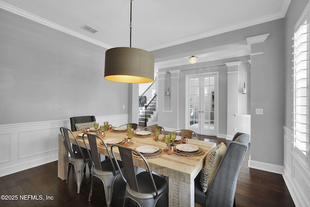 dining room featuring dark wood-type flooring, crown molding, french doors, and decorative columns