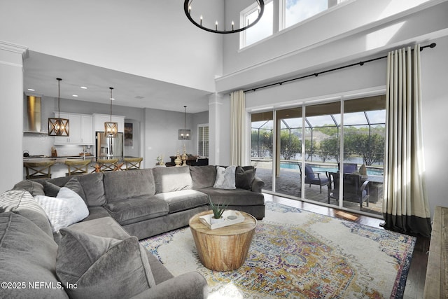 living room featuring hardwood / wood-style floors, a towering ceiling, and a notable chandelier