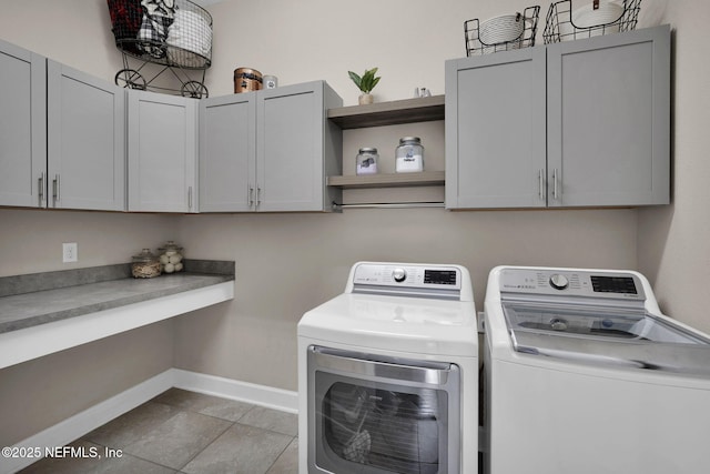 laundry area featuring light tile patterned flooring, washer and clothes dryer, and cabinets