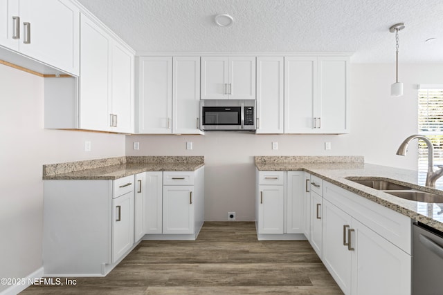 kitchen featuring appliances with stainless steel finishes, decorative light fixtures, sink, and white cabinets