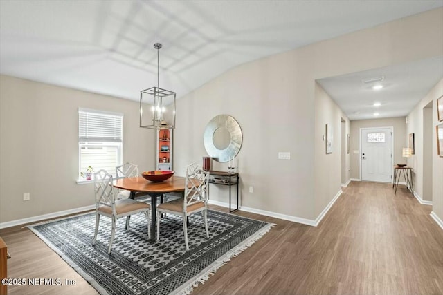 dining space featuring dark wood-style floors, vaulted ceiling, a notable chandelier, and baseboards