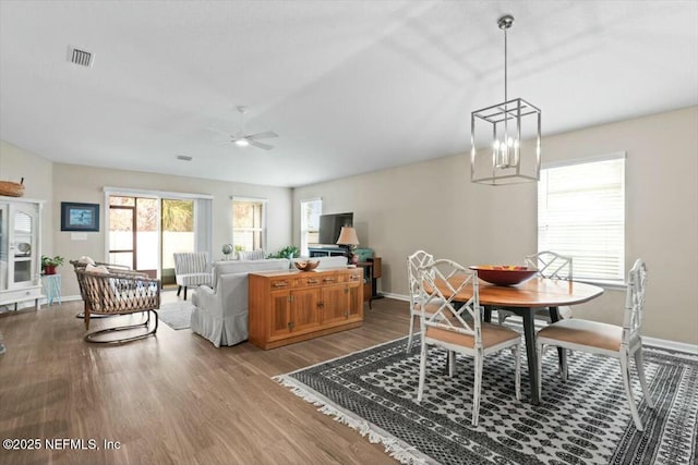 dining area featuring light wood-style floors, baseboards, visible vents, and ceiling fan with notable chandelier