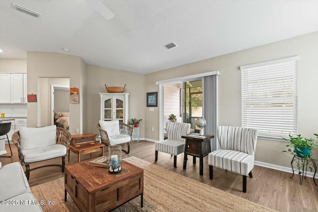 living room with light wood-style flooring, visible vents, and baseboards