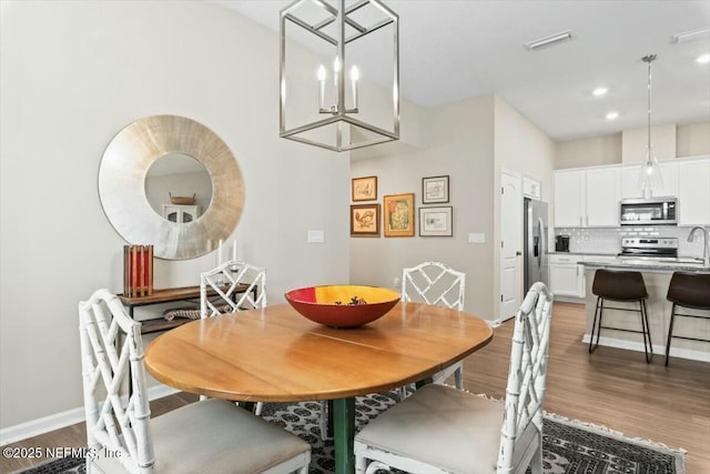 dining room with dark wood-style flooring, a notable chandelier, recessed lighting, visible vents, and baseboards