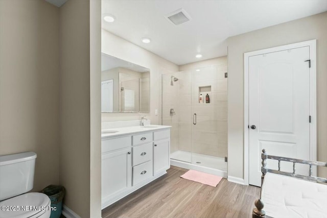 full bath featuring visible vents, toilet, wood finished floors, a shower stall, and a sink