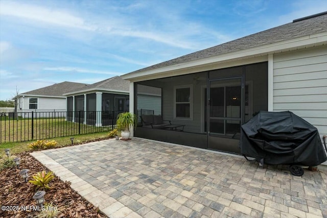 view of patio with area for grilling, fence, and a sunroom