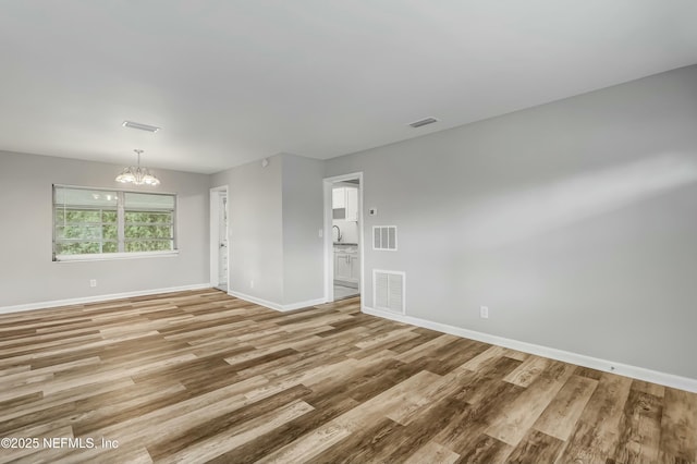 unfurnished room with a notable chandelier, sink, and light wood-type flooring