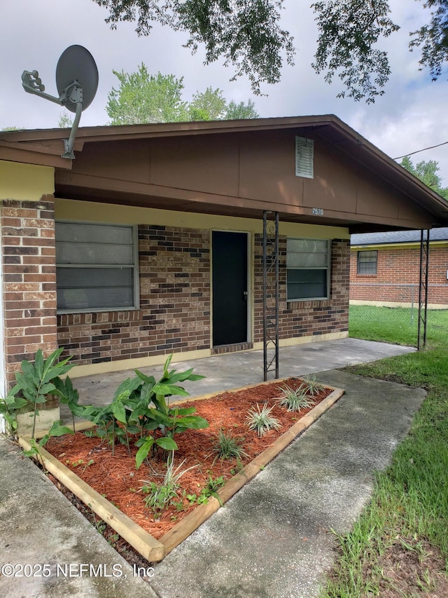 single story home featuring a porch and brick siding