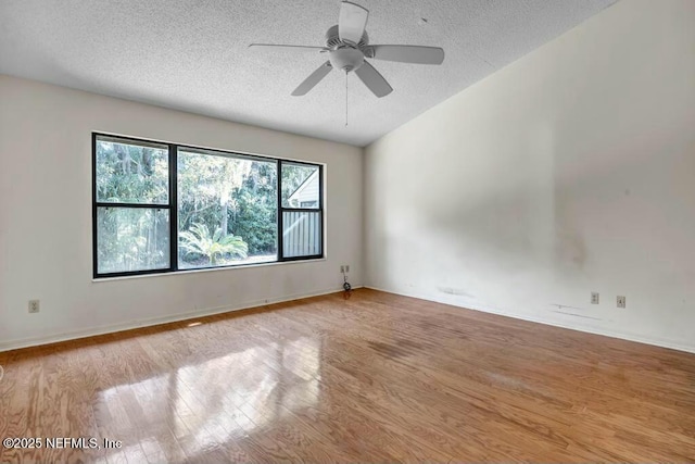 empty room featuring light wood-type flooring, vaulted ceiling, a textured ceiling, and ceiling fan