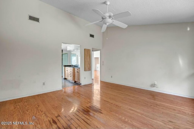 interior space with light wood-type flooring, high vaulted ceiling, ceiling fan, and a textured ceiling