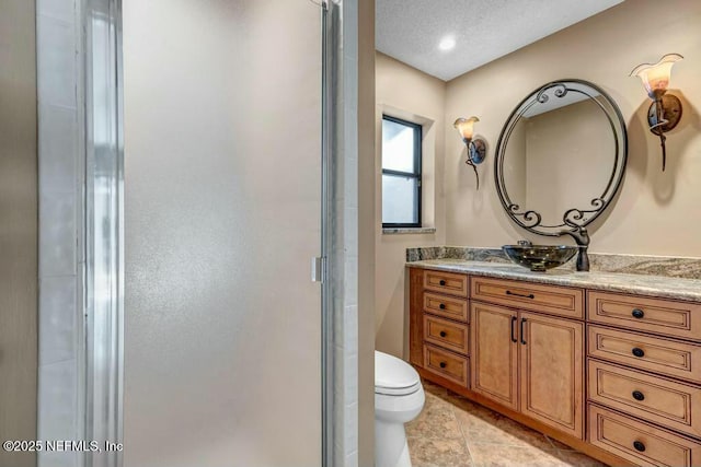 bathroom with toilet, a shower with shower door, a textured ceiling, tile patterned floors, and vanity