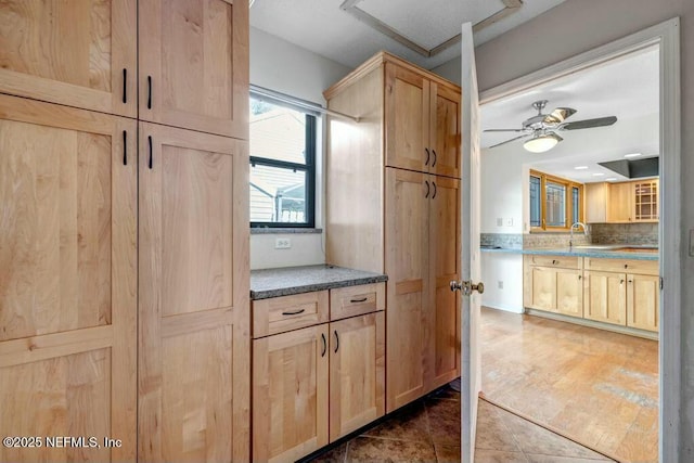 kitchen featuring dark tile patterned floors, light brown cabinetry, and decorative backsplash