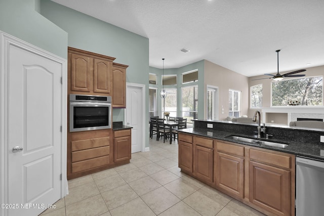 kitchen featuring stainless steel appliances, brown cabinetry, a sink, and a healthy amount of sunlight