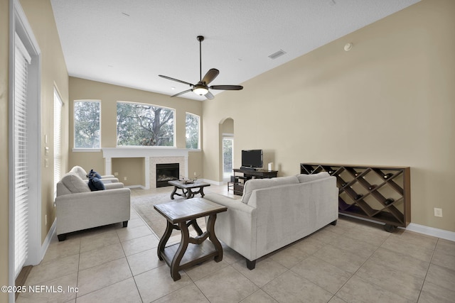 living area with ceiling fan, light tile patterned floors, visible vents, baseboards, and a tiled fireplace