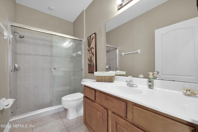 bathroom with toilet, vanity, a textured ceiling, a shower stall, and tile patterned floors