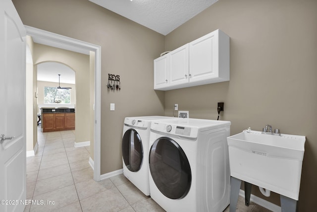 laundry area featuring cabinet space, washing machine and dryer, light tile patterned flooring, a sink, and baseboards