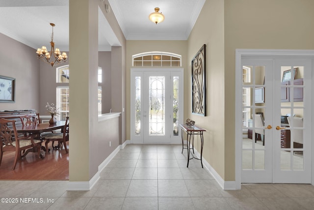 foyer entrance with light tile patterned floors, crown molding, and french doors